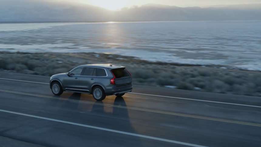 An suv travels on a coastal road at sunset