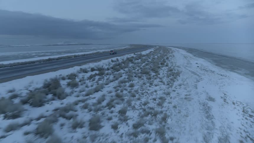 Car travels along snow lined highway