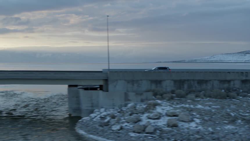 Car drives over a rural bridge at sunset