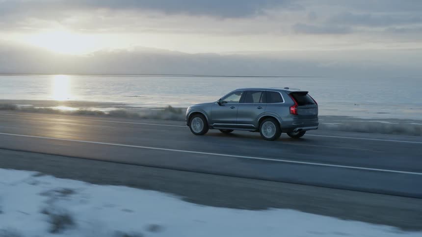 Vehicle travels down a road next to the lake