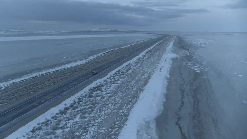 Car travels along snow lined highway