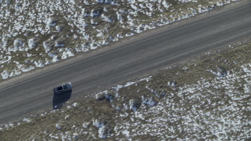 Vehicle travels down a highway next to snow covered fields