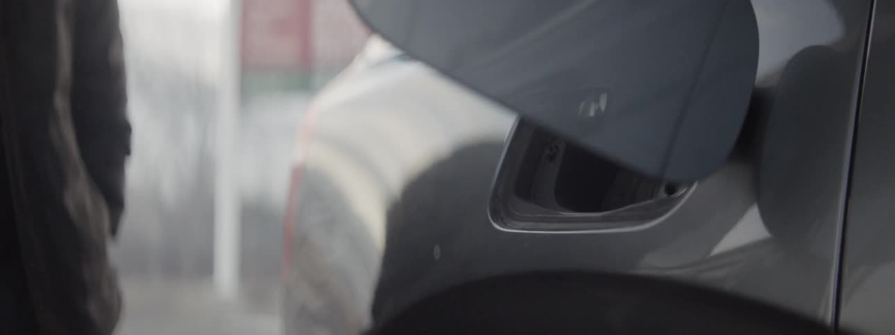 Man adds fuel to a car at a gas station