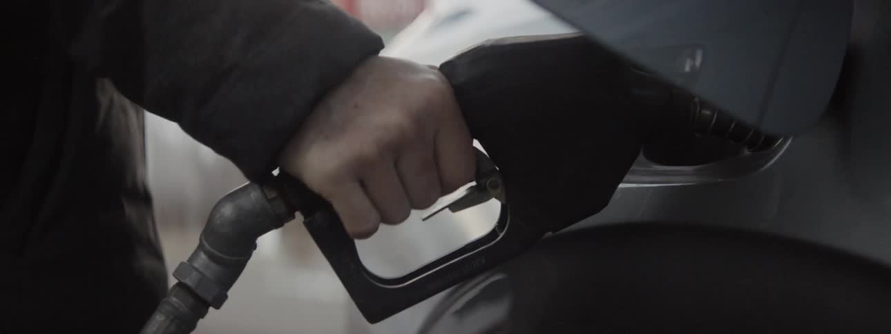Person pumps gas into a vehicle and closes the gas tank door