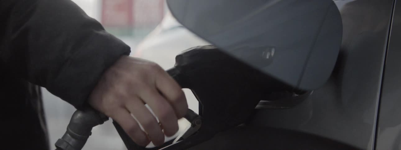 Person opens door to gas tank and inserts nozzle