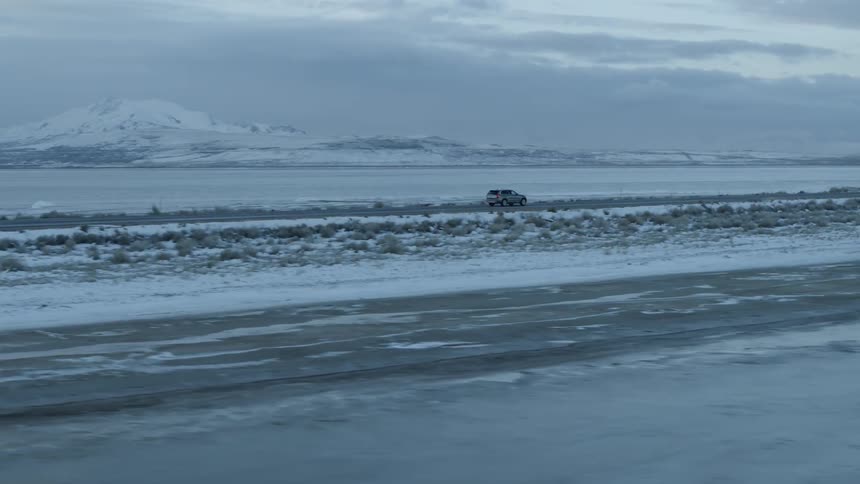 Vehicle travels down a highway between snow covered fields