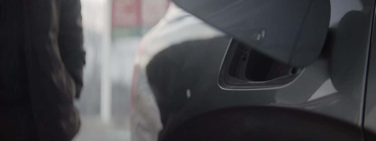 A man removes a gas nozzle from a cars tank
