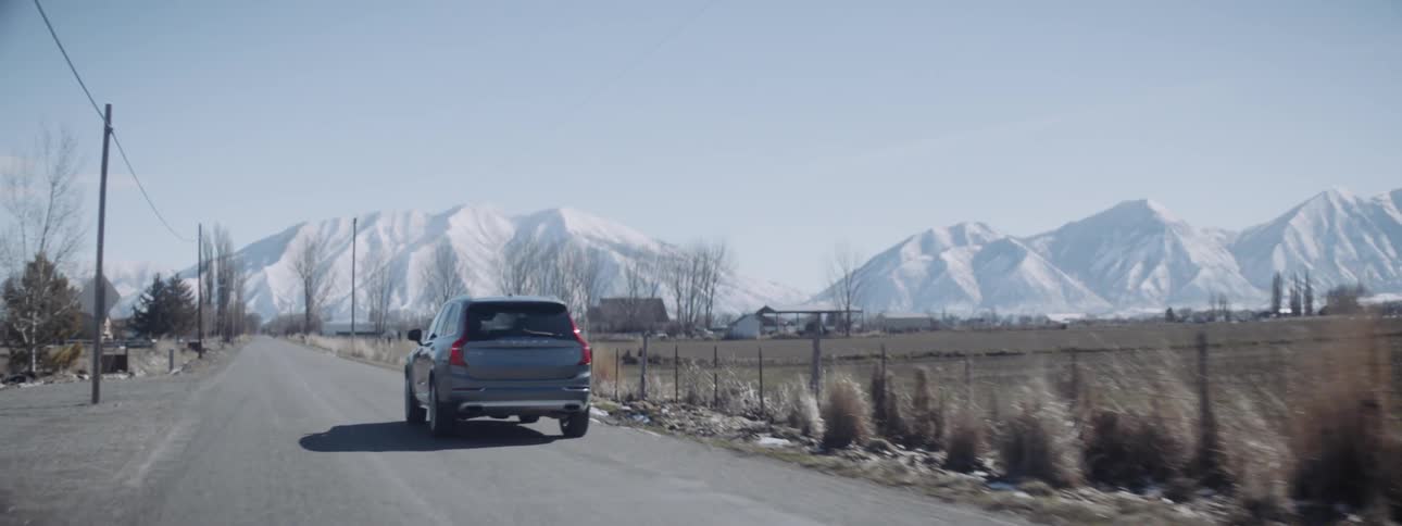 A truck drives towards snow covered mountains