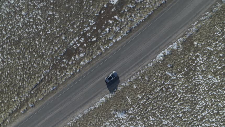 Vehicle travels next to a snowy field