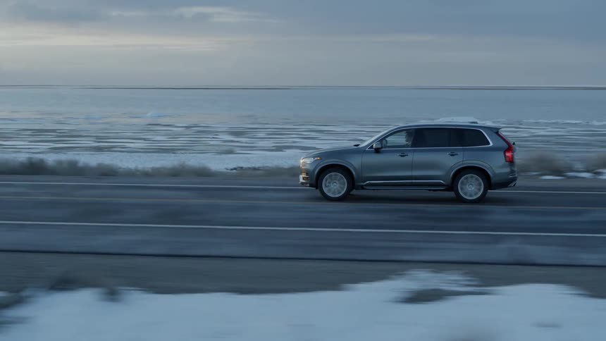 Vehicle travels down a road next to a snowy field