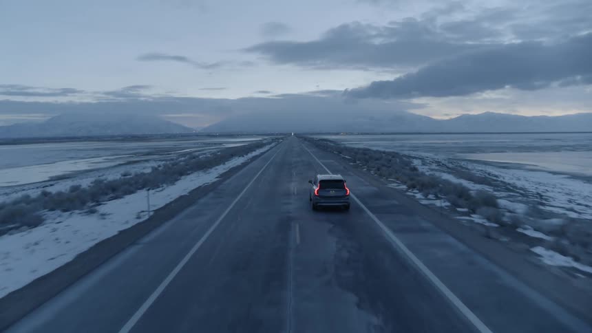 A vehicle travels on a rural road at sunset