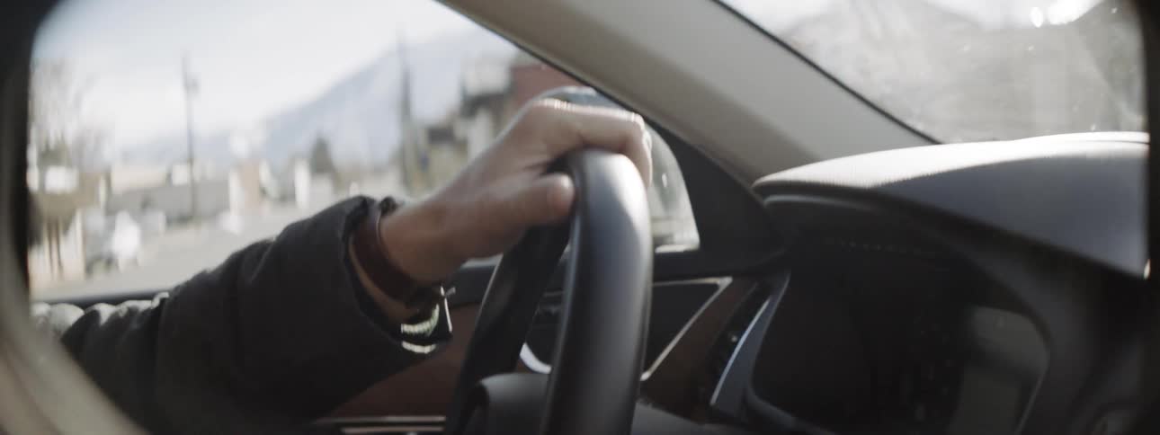 Man looks around as he drives a car down the street