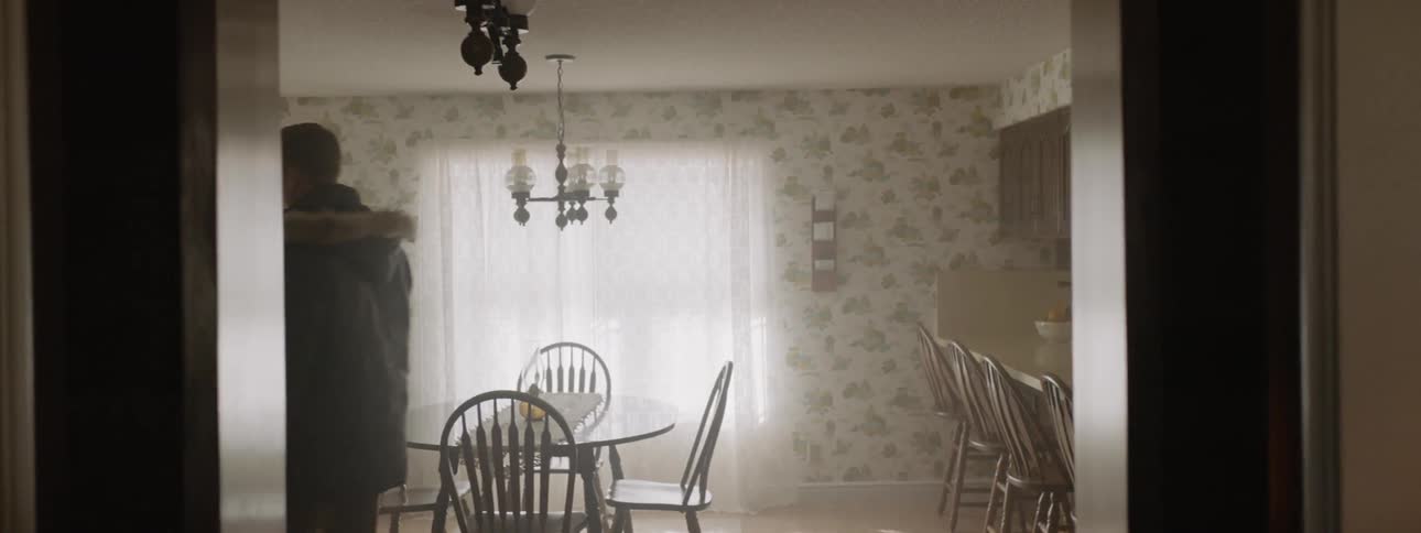 Man wearing a hooded jacket walks through the dining room