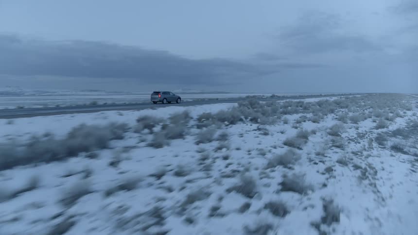 Car drives past snow covered plains