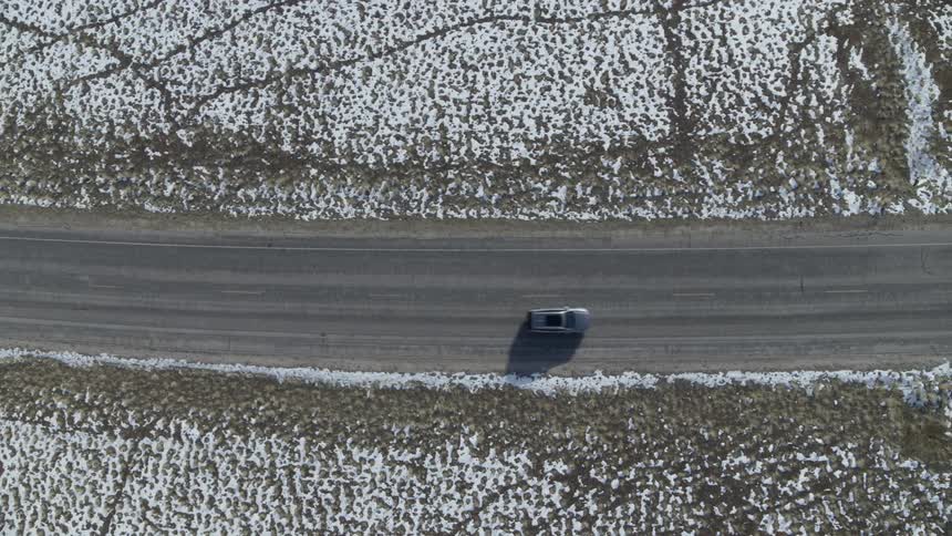 Vehicle travels down a highway next to snow covered fields