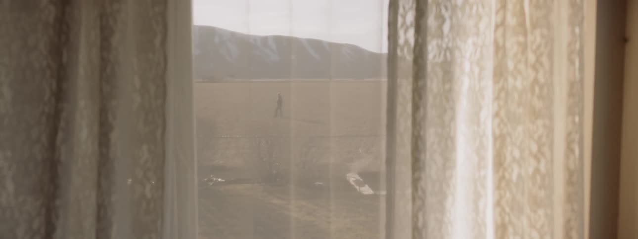 Man walks in a field outside of a building