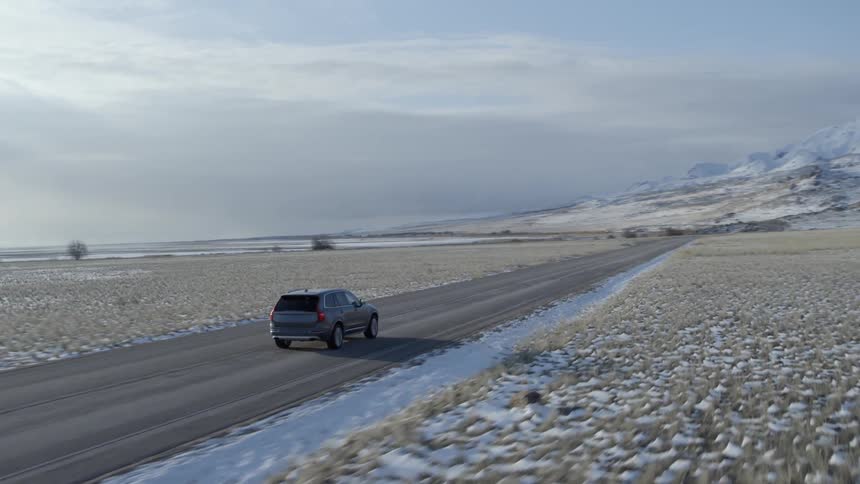 A truck drives towards snow covered mountains