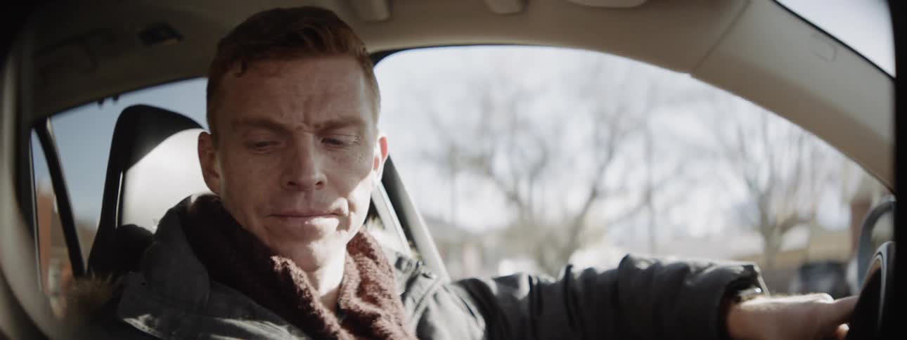 A man is driving a car through a neighborhood on a cold day