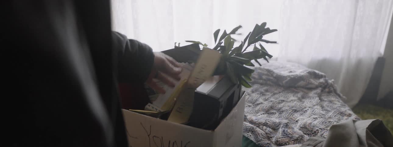 Man looks at a cardboard box of personal belongings