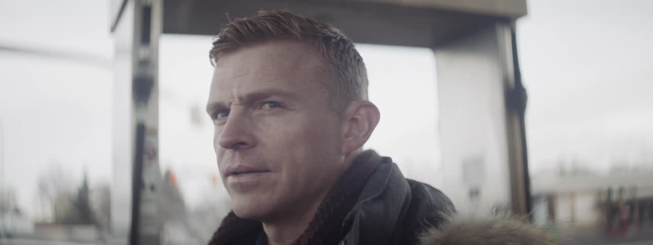 A man is shaking off the cold as he stands outside in daylight