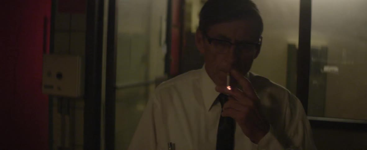 Man lights up a cigarette in a bare office