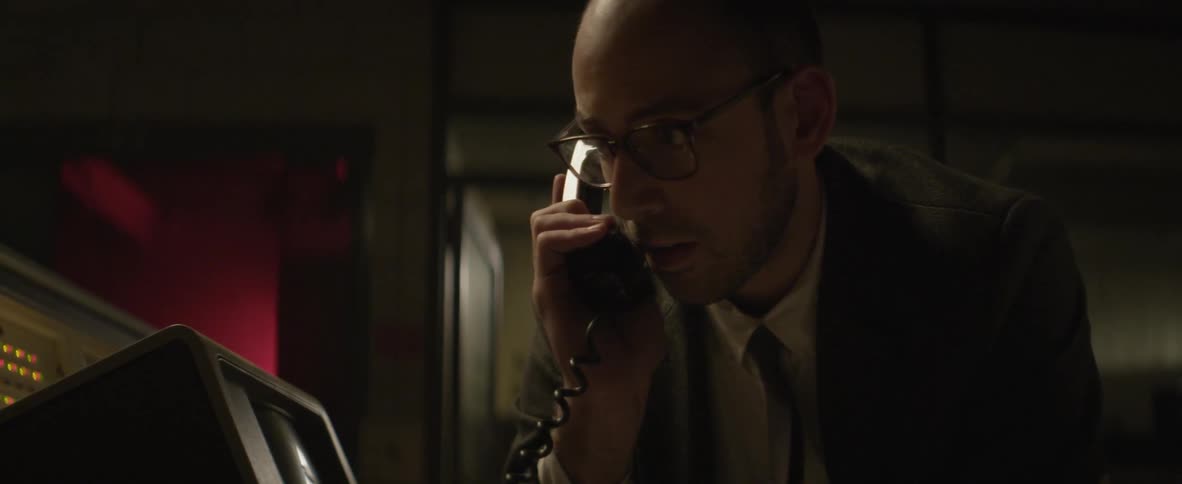 A man in a suit talking on a corded phone