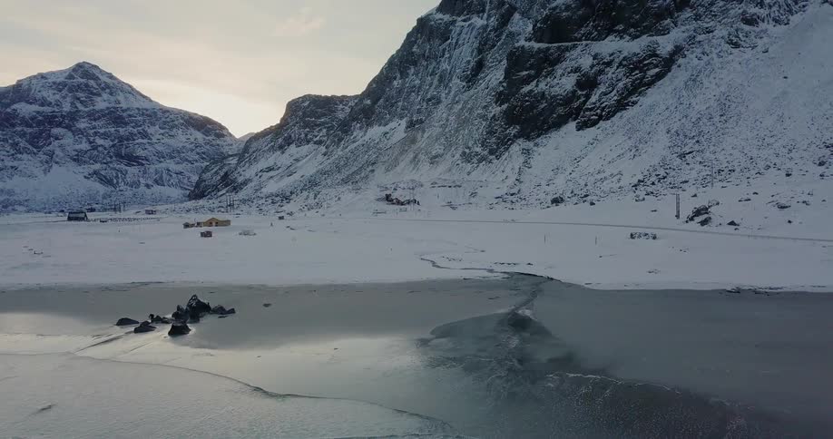 Waves wash ashore a snowy beach at sunset