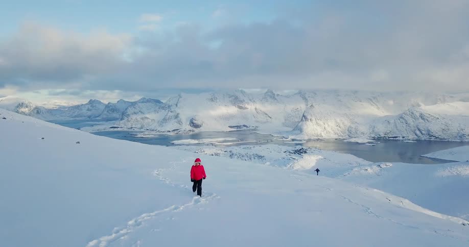 Man walks through the snow under a cloudy blue sky