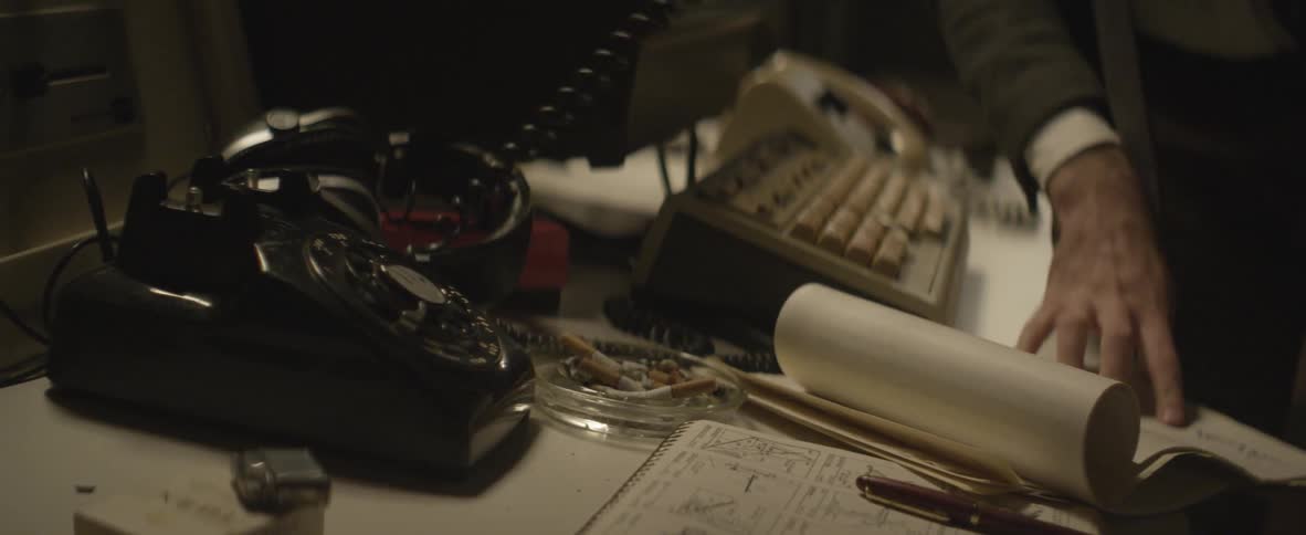 Person at a desk picks up a phone and dials