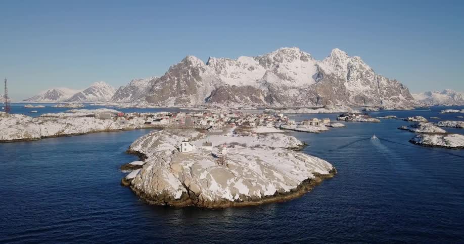 Boat cruises on the open water near snowy islands and mountains