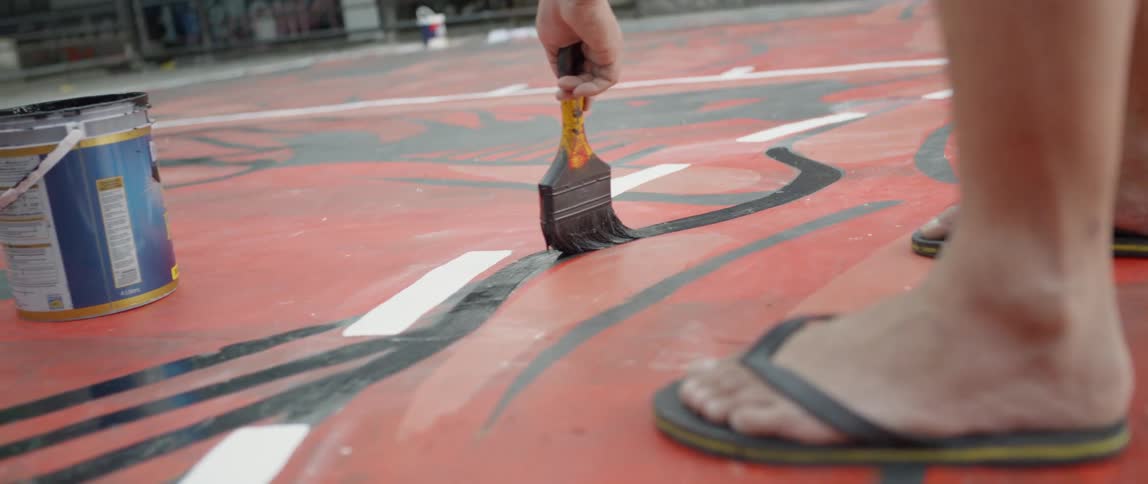 Person paints black lines on the ground