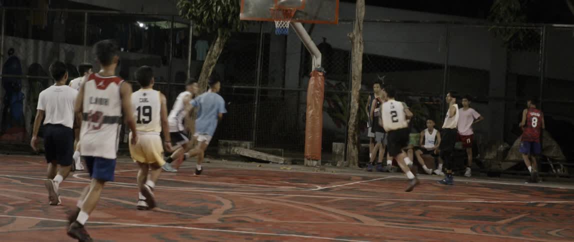 People are playing basketball on the court at night