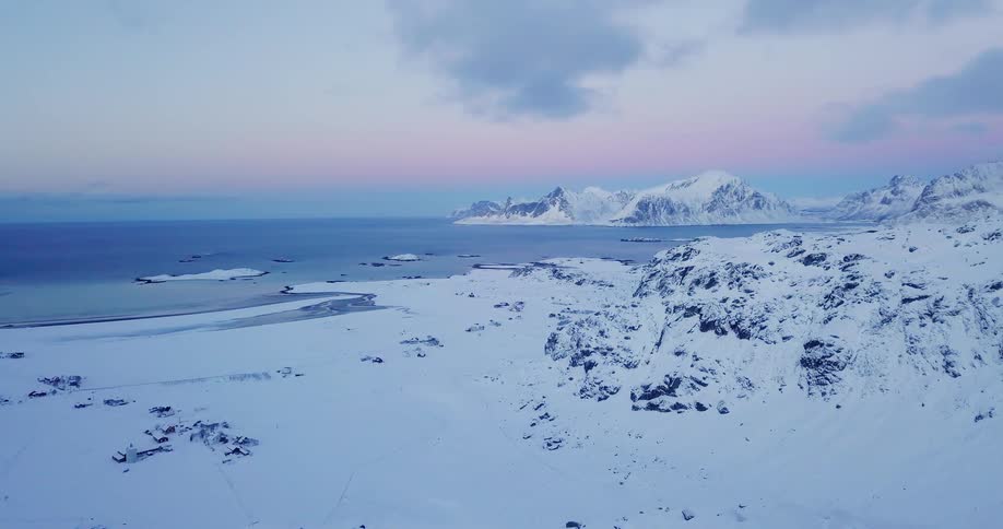 Snow covers a coastal mountain landscape at sunrise