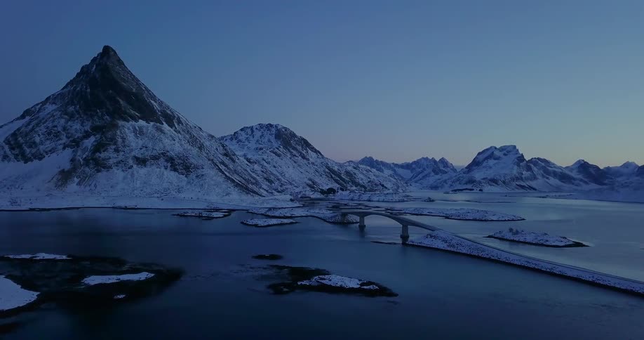 Snowy mountains surround a lake at dusk