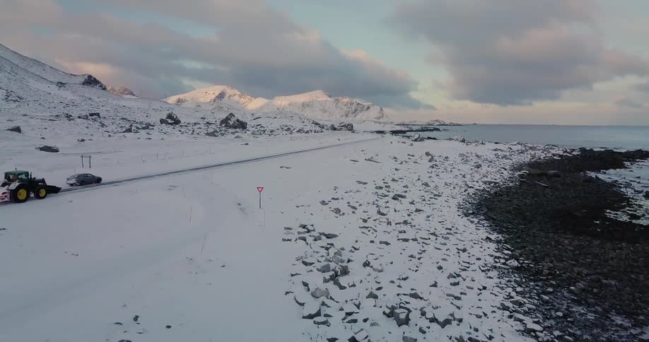 Cars travel on a snowy rural road at sunrise