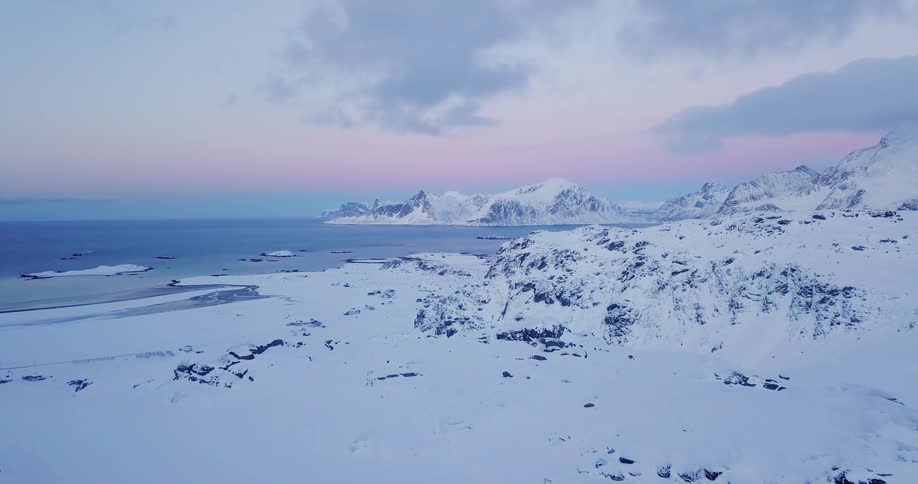 The sun sets over a snowy coastline