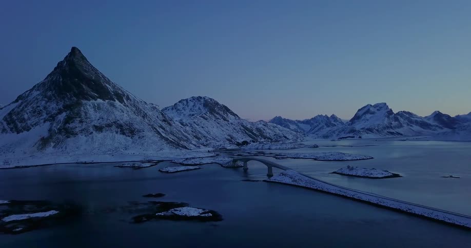 Snowy mountains surround a lake at dusk