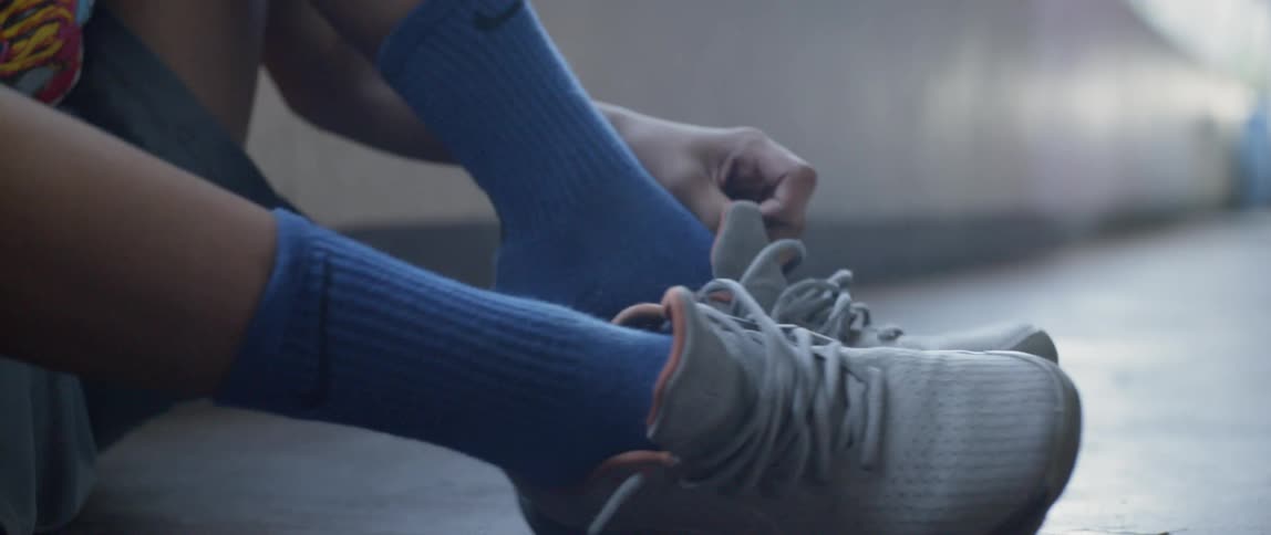 An person is putting on his sneakers inside a hallway in daylight