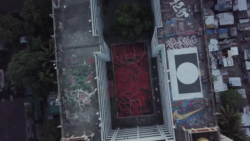 A basketball court in a courtyard is painted red and black