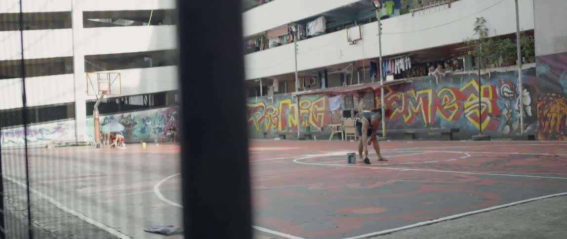Man paints on an outdoor basketball court