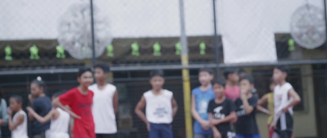A boy runs on a basketball court while other children look on