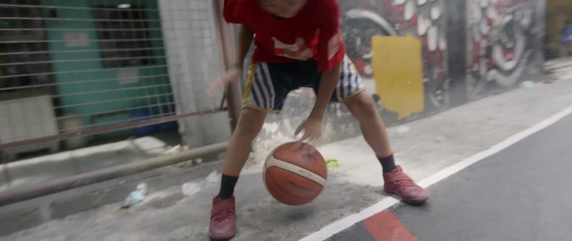 Boy dribbles a basketball on an outdoor court