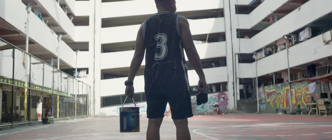 Man holds a paint bucket and brush standing on a basketball court