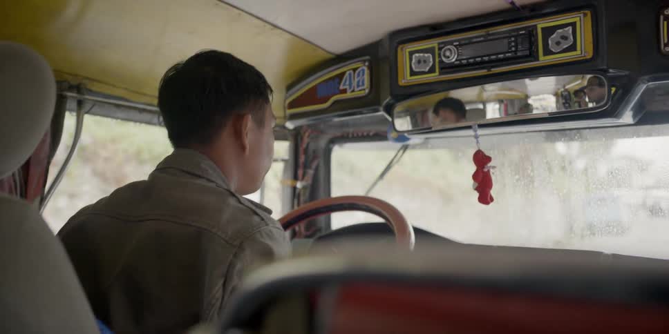 A man drives a bus on a rural road