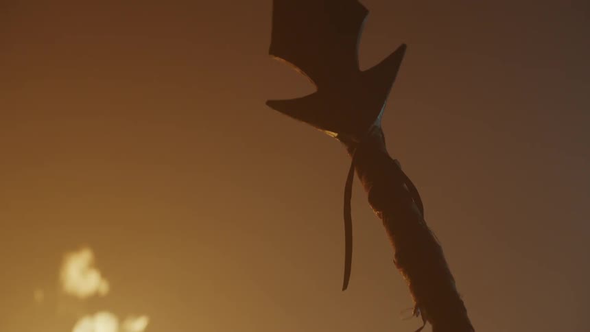 Person holding spear stands near torch
