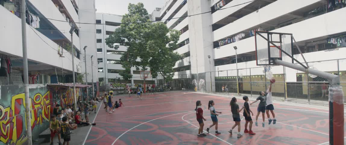 People watch on as children play basketball on the court