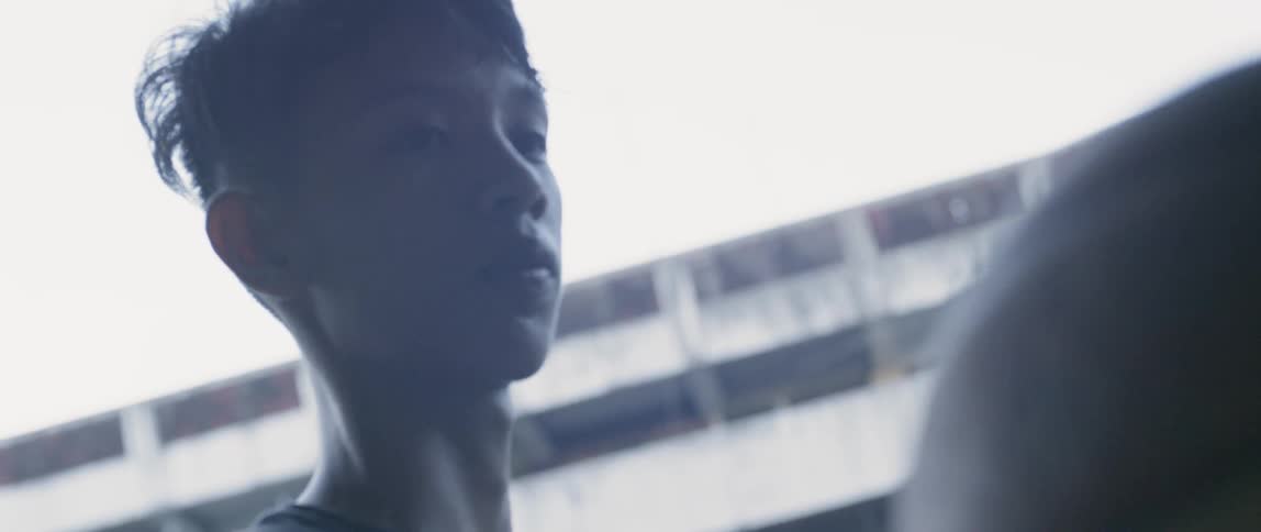 A boy holds and twirls a basketball on a sunny day