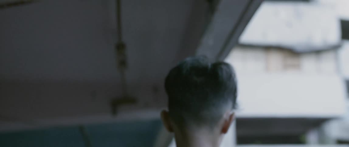 A teenage boy walks on an apartment balcony