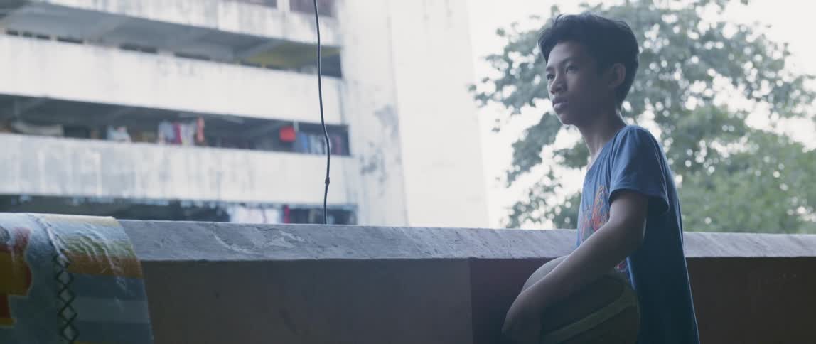 Boy stands on an apartment balcony with a basketball
