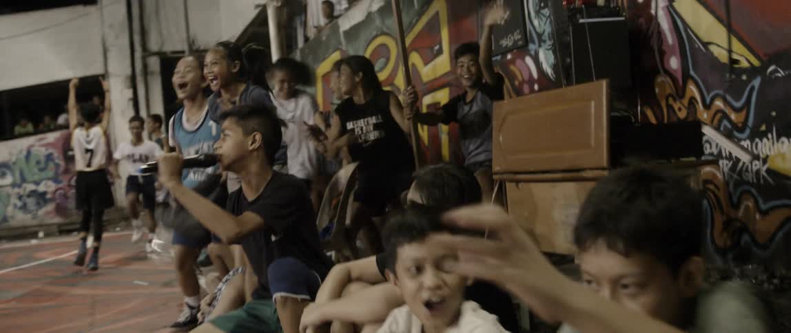 Kids cheer on the sidelines of a basketball court